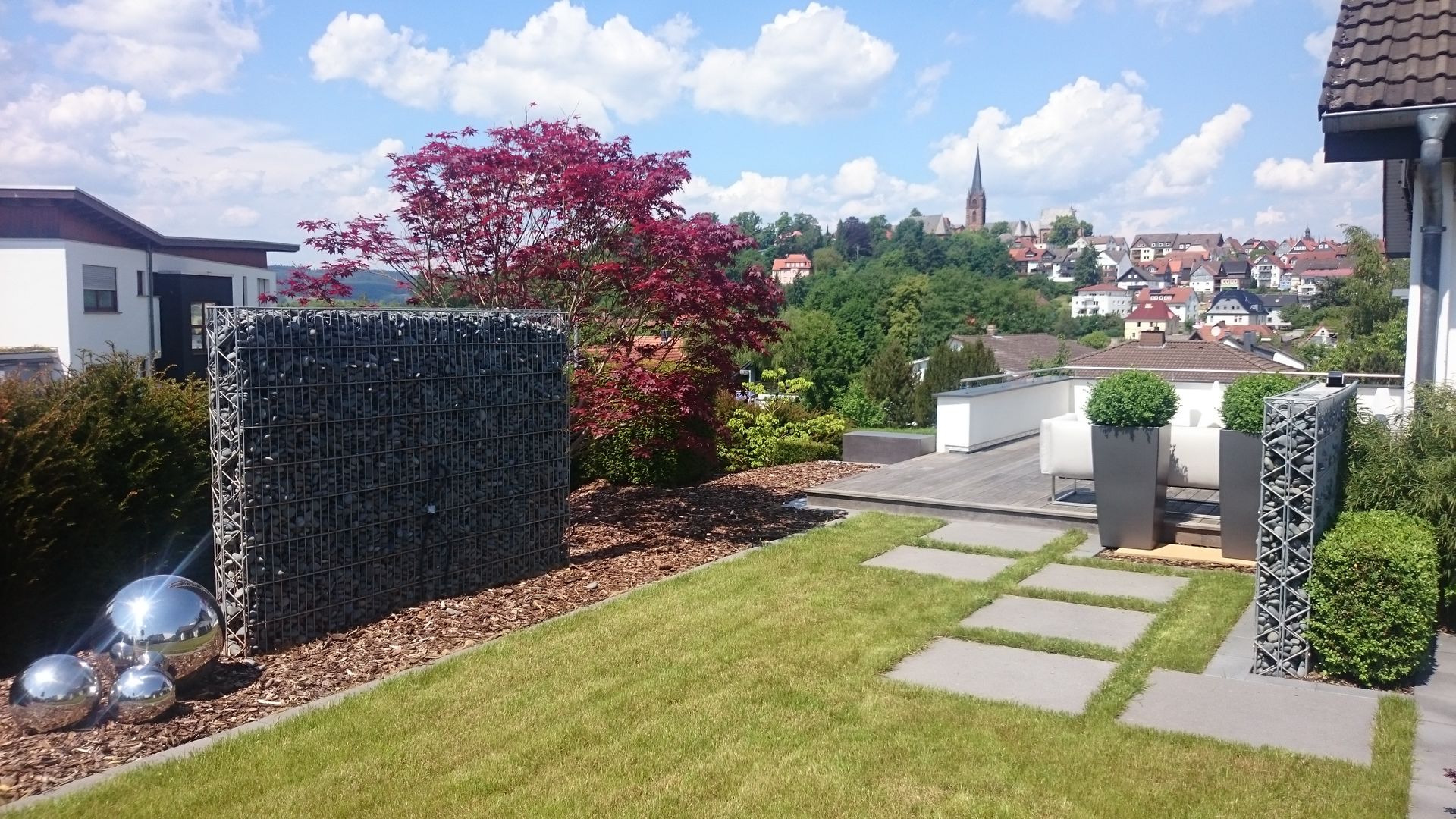 Moderne Dachterrasse mit Gabionenwand und Blick über die Stadt